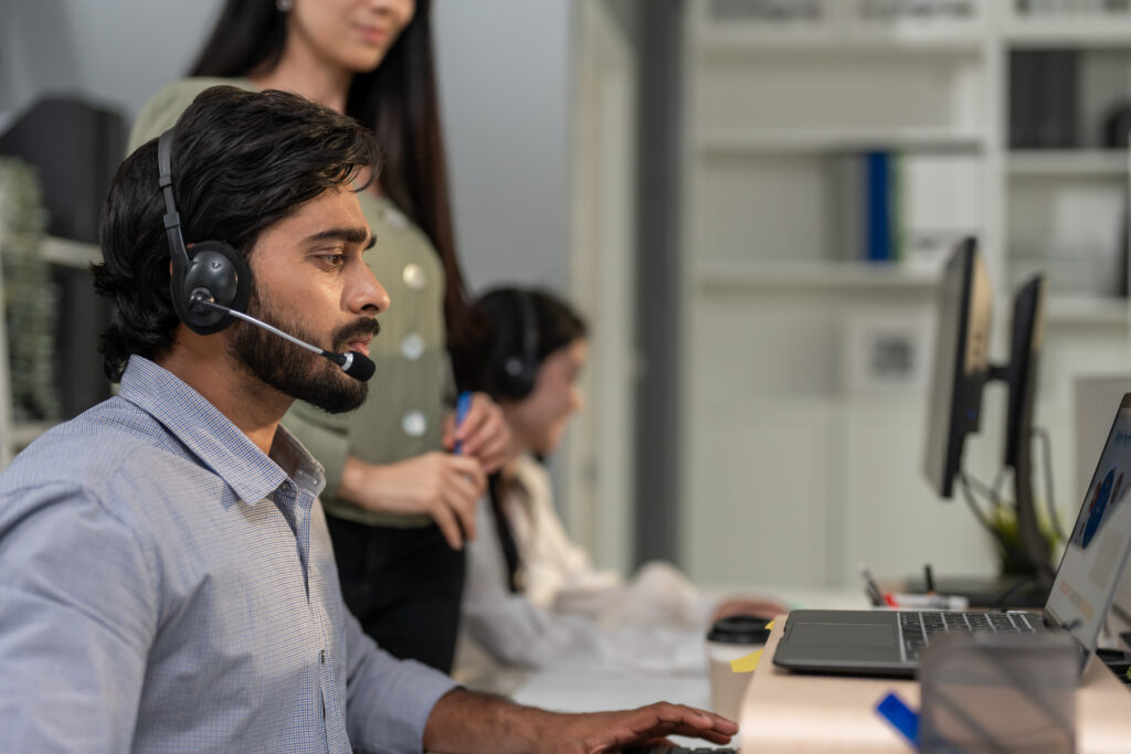 A focused  businessman with a phone headset works on a laptop, concentrating on providing high-quality Back Office BPO Services.
